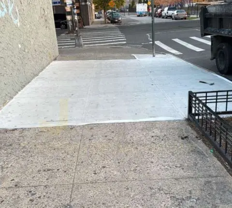 Fresh concrete sidewalk section at a street corner next to a crosswalk