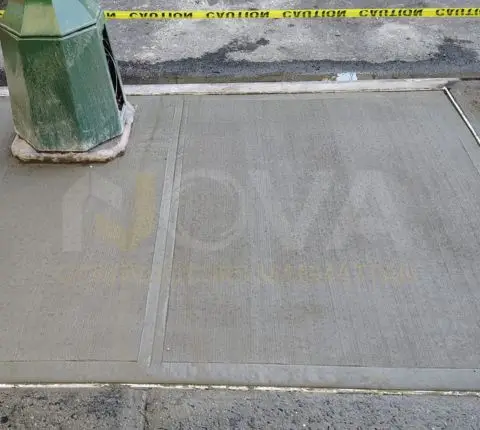 New sidewalk poured around a street-side utility box, cordoned off with caution tape