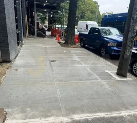 Wide replaced sidewalk along an apartment building with construction scaffolding