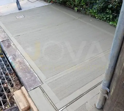 Curing concrete sidewalk slabs next to a curb drain grate